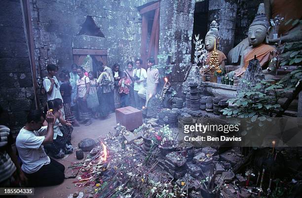 The Buddhist faithful worship in front of a statue of the Buddha inside the ruins of the Hindu Khmer temple of Wat Phu in Champassak province, Laos...