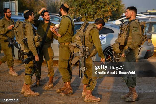 Soldier eats a sufgania as others gather nearby ahead of the eight night of Hanukkah at staging point near the Gaza border on December 14, 2023 in...