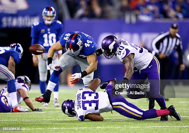 Running back Peyton Hillis of the New York Giants loses the ball as strong safety Jamarca Sanford and middle linebacker Erin Henderson of the...