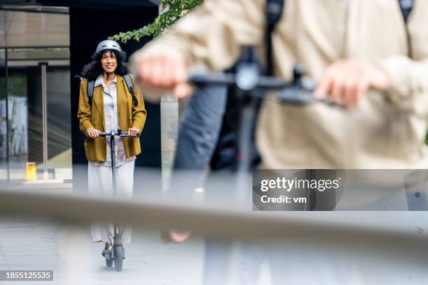 mujer montando scooter eléctrico - movilidad sostenible fotografías e imágenes de stock