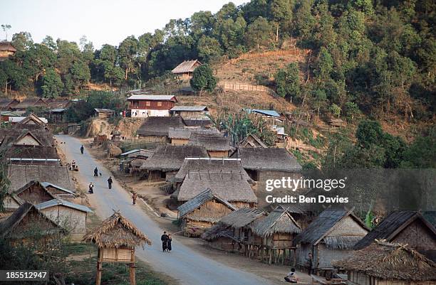 Hmong hilltribes people walk down the road in Ban Songcha, an enchanting village made up of traditional thached huts in Oudomxai Province, Northern...