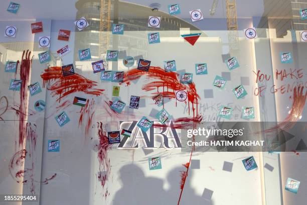 This photograph taken on December 17 in Brussels shows the window of a Zara clothes shop with red paint and stickers stuck on it during a...