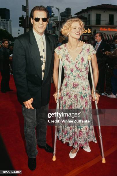 American actor Robert Davi, wearing a black jacket with a shirt and tie, and black jeans, and his wife Christine Bolster, who wears a floral pattern...