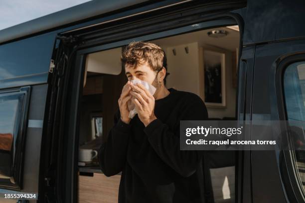 adult man suffering joy and blowing his nose at the door of a motorhome - hooikoorts stockfoto's en -beelden