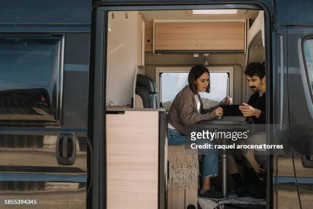 adult couple consulting something on his ipad in a camper van - torres stock pictures, royalty-free photos & images