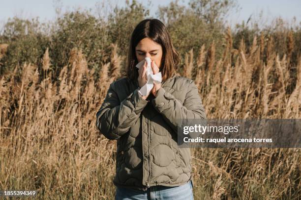 adult woman suffering spring allergy and blowing nose with a tissue in the nature - hayfever stock pictures, royalty-free photos & images