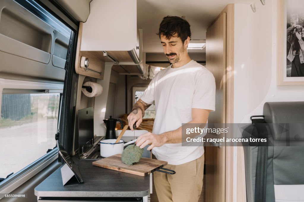 Adult man preparing food in a motorhome consulting a recipe on the ipad