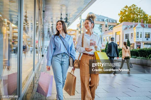 female friends looking at store window - fashion center stock pictures, royalty-free photos & images