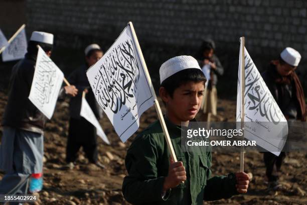 Afghan children from a Madrassa or an Islamic school hold Taliban's flag in Fayzabad district of Badakhshan province on December 17, 2023.