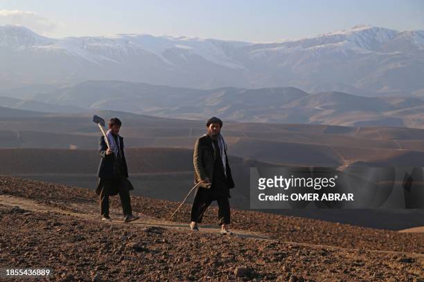 Afghan men walk along a path on the outskirts of Fayzabad district in Badakhshan province on December 17, 2023.