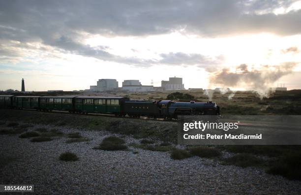 Evening sunlight bathes Dungeness nuclear power station as a steam train from the Romney, Hythe and Dymchurch railway passes by on October 21, 2013...