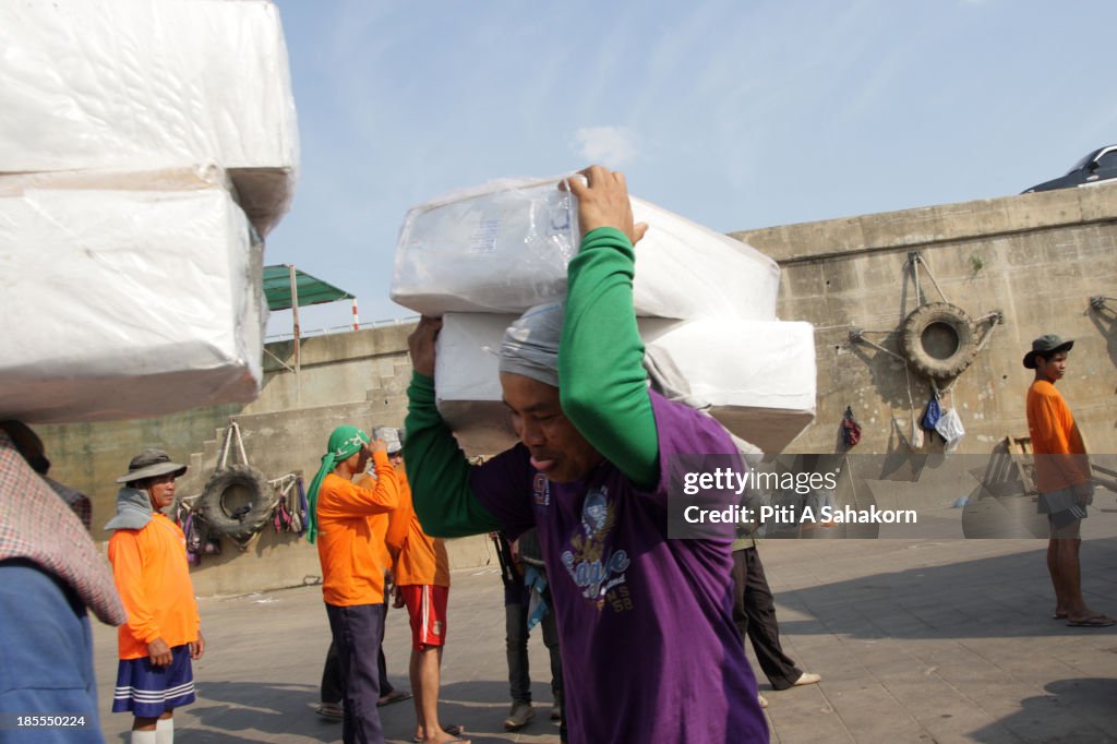 Lao workers carry goods from boats docked at Chiang Saen...