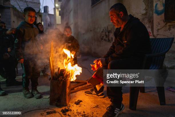 Man tends to a fire for his family outside of their damaged home in Jenin following a muilti-day raid in the city by members of the Israeli Defense...