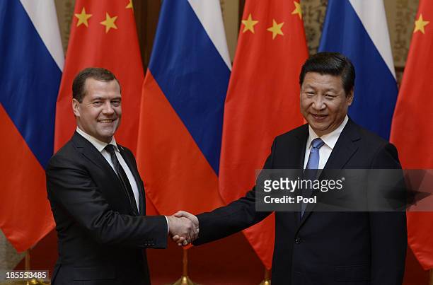 Russian Prime Minister Dmitry Medvedev shakes hands with Chinese President Xi Jinping before a meeting at the Great Hall of the People on October 22,...