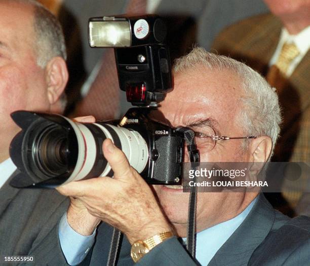 Syrian Defence Minister Gen. Mustafa Tlass takes a photo with an AFP photo-journalist's camera during a lecture for Palestinian poet Samih al-Kassem...
