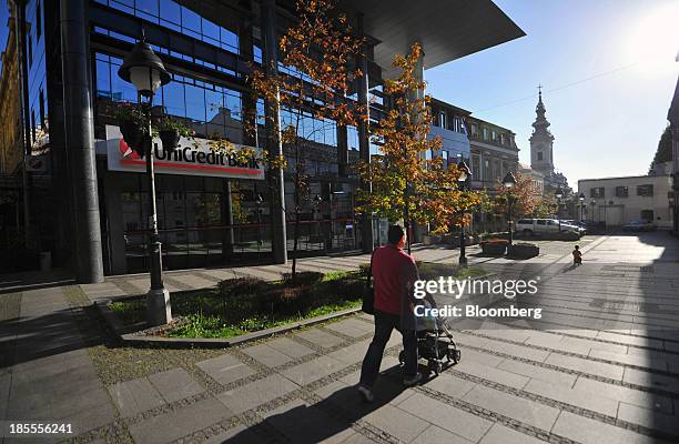 Pedestrian pushes a baby stroller passed a UniCredit SpA office in Belgrade, Serbia, on Sunday, Oct. 20, 2013. Serbia's government revealed a salvo...