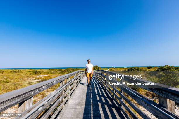 happy man in sunglasses walking on boardwalk in bill baggs cape florida state park, florida, usa - florida state v miami stockfoto's en -beelden