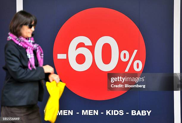 Pedestrian passes a discount sign in the window of a Gap Inc. Fashion clothing store in Belgrade, Serbia, on Monday, Oct. 21, 2013. Serbia's...