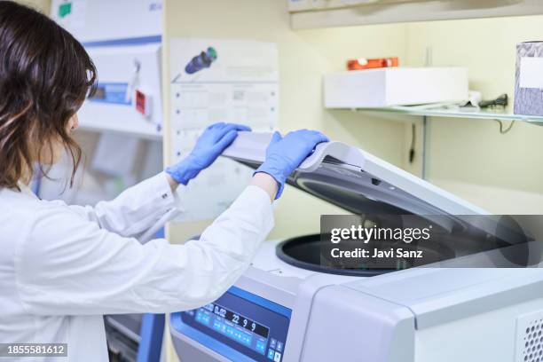 female biologist putting tubes in centrifuge - centrifuge stock pictures, royalty-free photos & images