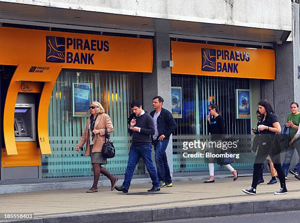 Pedestrians pass a branch of Piraeus Bank SA in Belgrade, Serbia, on Monday, Oct. 21, 2013. Serbia's government revealed a salvo of measures to bring...