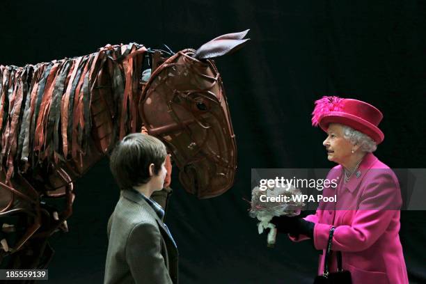 Britain's Queen Elizabeth II receives flowers from a child actor as she inspects the horse prop from the theatre production 'War Horse' during a...