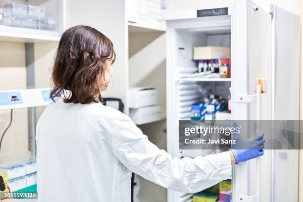 lab technician storing blood samples in fridge for later use - amostra médica imagens e fotografias de stock