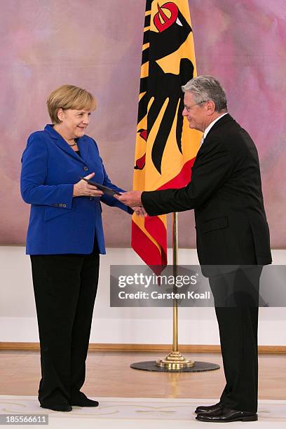German President Joachim Gauck hands German Chancellor Angela Merkel her dismissal certificate at a ceremony for the outgoing German government at...
