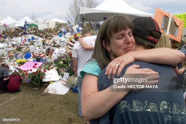 Littleton residents hug each other, 26 April 1999, as they visit the makeshift memorial built in Clement Park to remember those who died in the...