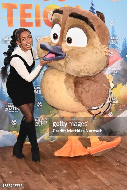 Aminata Belli and a mascot attend the Berlin premiere of "Raus aus dem Teich" at Zoo Palast on December 17, 2023 in Berlin, Germany.