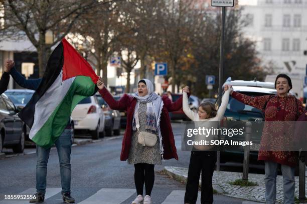 Activists hold Palestinian flags while shouting anti-war slogans during a demonstration near the Israeli embassy. The protest actions were organized...