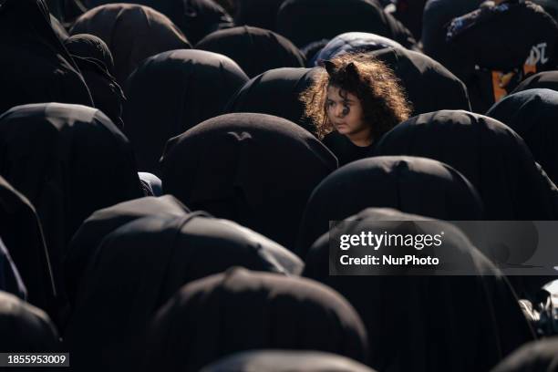 Young girl is looking on as veiled Iranian women are praying during a religious ceremony to commemorate the death anniversary of Fatima, the daughter...