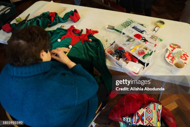 Woman sews an elf costume for the Black Santa's Grotto experience on December 15, 2023 in London, England. The annual "Noir Kringle" Black Santa's...