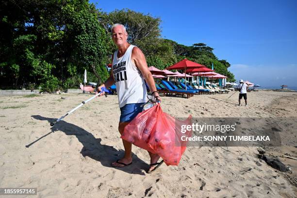Australian national Paul Gibson collects plastic waste along a beach in Sanur, Indonesia's Bali island, on December 18, 2023.