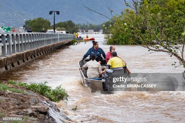 Residents cross floodwaters by boat in Cairns on December 18, 2023. Flash floods swamped northeastern Australia on December 18, with raging waters...
