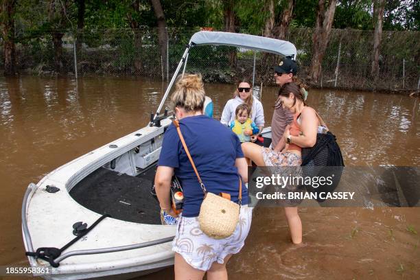 People prepare to return to their flooded residential area by boat in Cairns on December 18, 2023. Flash floods swamped northeastern Australia on...