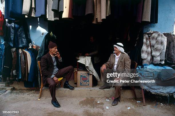 Men chat outside a clothes shop in a war torn street in the Shatilla Palestinian refugee camp during the civil war..