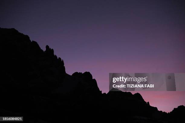 The sky turns purple behind the mountains as the sun rises before the first run of the men's Giant Slalom, during the FIS Alpine Ski World Cup in...