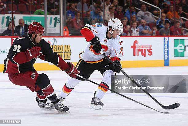 Brodie of the Calgary Flames skates with the puck under pressure from Brandon Yip of the Phoenix Coyotes during the second period of the NHL game at...