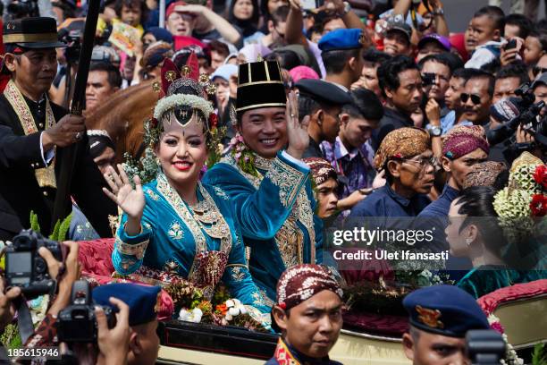Gusti Kanjeng Ratu Hayu and KPH Notonegoro wave to crowds while on their journey by carriage during the wedding ceremony parade as part of the Royal...