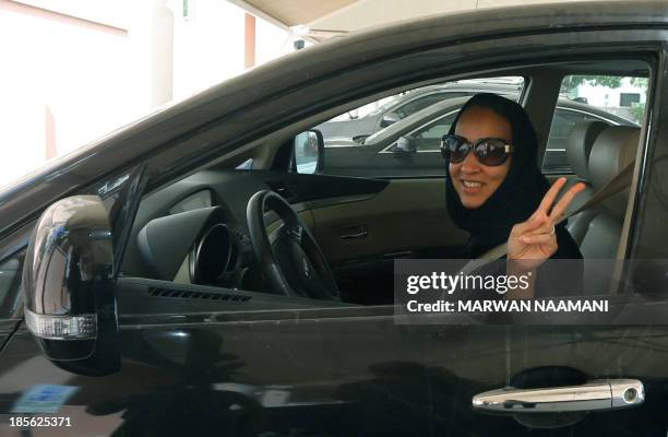 Saudi activist Manal Al Sharif, who now lives in Dubai, flashes the sign for victory as she drives her car in the Gulf Emirate city on October 22 in...