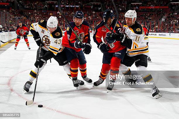 Matt Bartkowski of the Boston Bruins skates with the puck while teammate Gregory Campbell tangles with Scott Gomez and Kris Versteeg of the Florida...