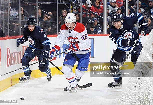 Daniel Briere of the Montreal Canadiens plays the puck behind the net as Paul Postma and Blake Wheeler of the Winnipeg Jets give chase during third...