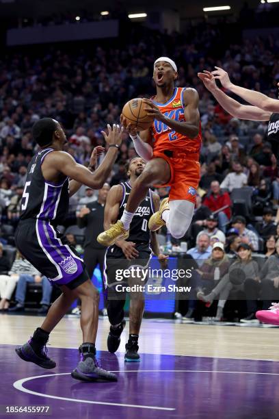 Shai Gilgeous-Alexander of the Oklahoma City Thunder looks to pass around De'Aaron Fox of the Sacramento Kings in the first half at Golden 1 Center...