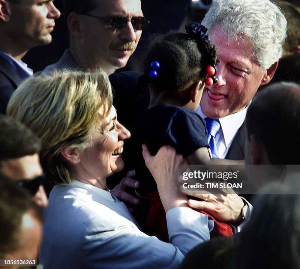 President Bill Clinton receives a baby girl from First Lady Hillary Clinton while the two greeted several hundred people who came out to Syracuse...