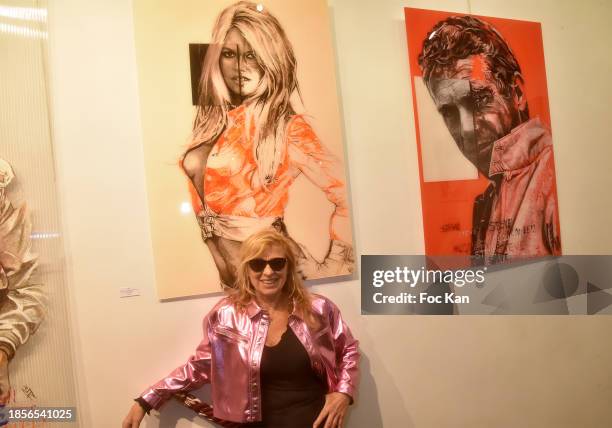 Artist Natacha Toutain poses with her portraits of Steve McQueen and Brigitte Bardot during Paris Arty Show Edition XIII at Galerie Francis Barlier...