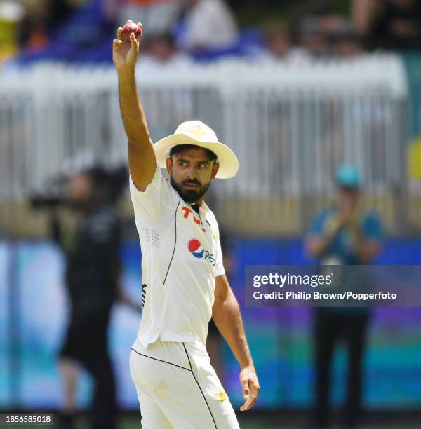 Aamer Jamal holds up the ball as he leaves the field after taking his sixth match wicket during day two of the Men's First Test match between...