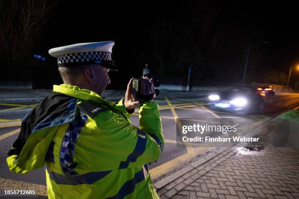 Police officer uses a speed gun looking for traffic violations during the operation, on December 14, 2023 in Bridport, England, Drink and drug...