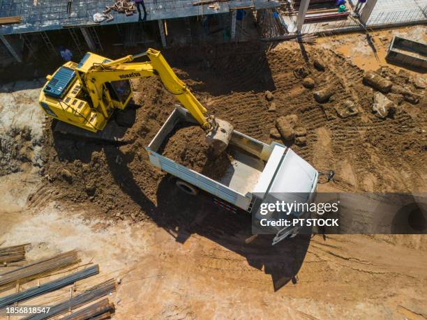 aerial view an excavator is loading dirt into a truck. - camion benne photos et images de collection