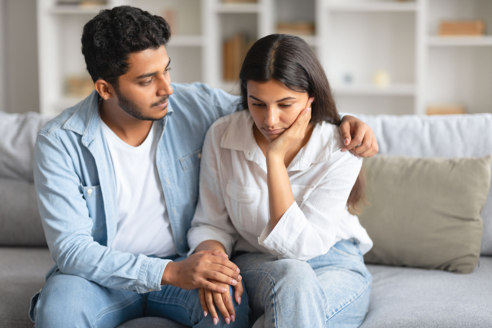 Caring indian husband soothing his distressed wife on sofa Caring indian husband soothing his distressed wife on sofa