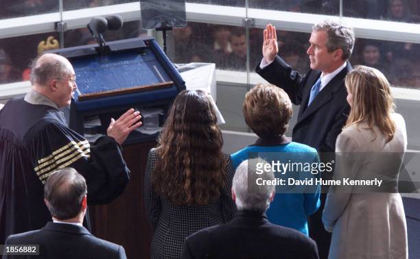 President George W. Bush takes the oath of office administered by Chief Justice William Rehnquist at his inauguration while his wife and family look...